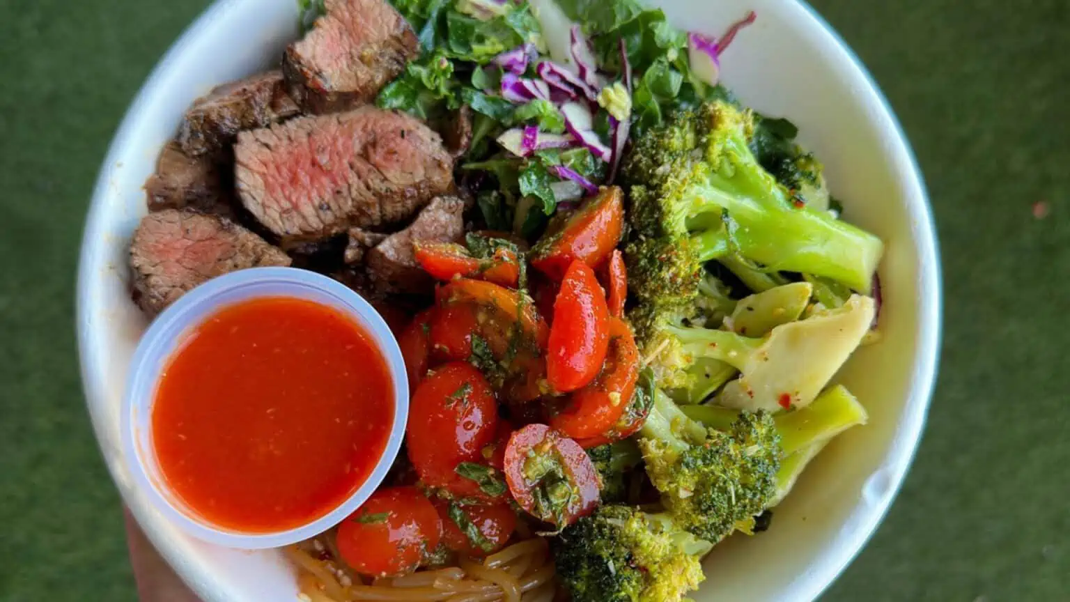 A fresh kitchen bowl with steak, tomatoes, broccoli, and more