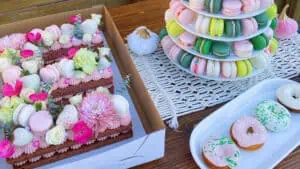 Dessert table with a tower of french macarons, gluten-free donuts, and a cake shaped like the letter E and decorated with gluten-free macarons and other baked goods