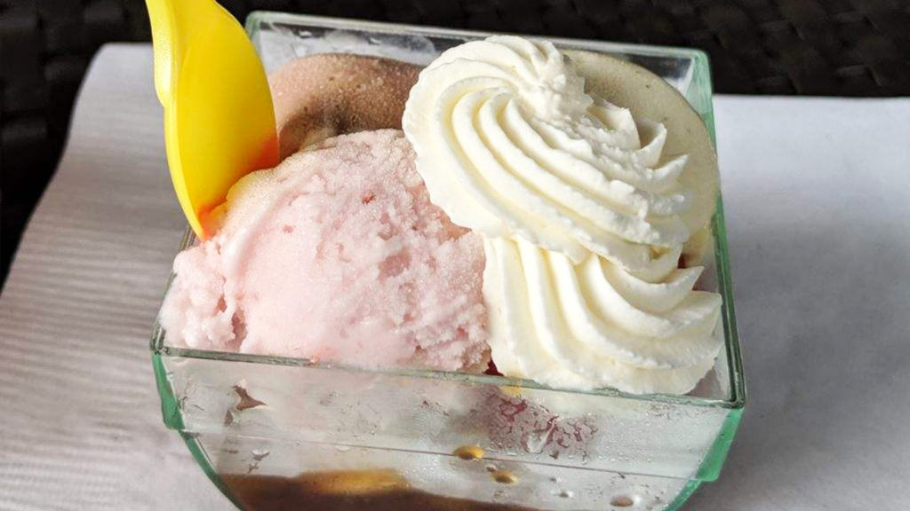 Multiple flavored scoops of Ice cream in a clear dish.