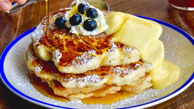 Stack of pancakes covered in syrup and blueberries