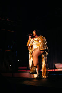 Lizzo dances while she sings into a microphone on stage