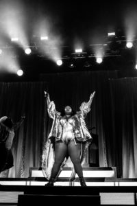 A black and white photo of Lizzo with her arms raised