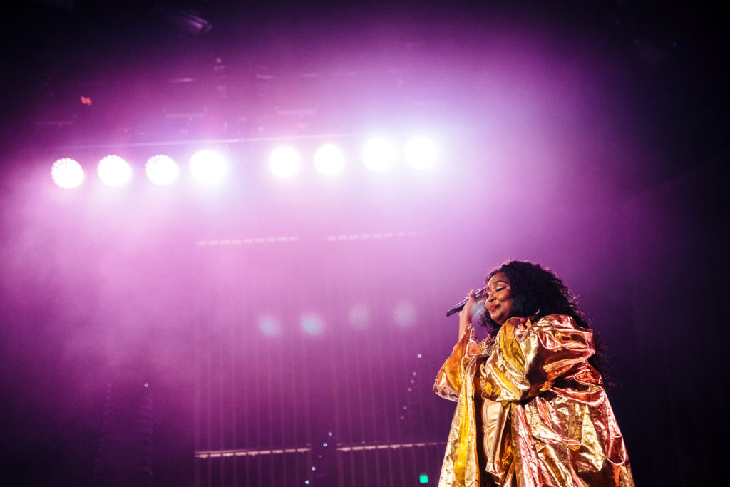 Surrounded by purple and white lights, Lizzo takes a moment to soak in the crowd's applause