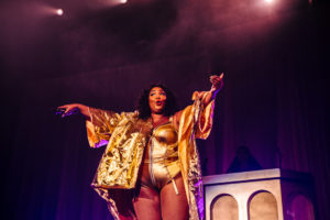 Lizzo gesturing to the crowd during her concert to sing along with her