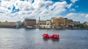 Photo of a red pirate ship in the water outside a downtown area