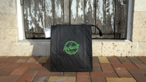 A black rebuilt meals insulated bag sitting in front of a wooden front door of a house