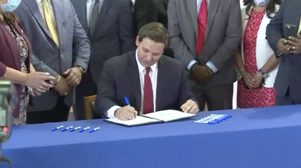 Photo of governor signing a bill at a blue table