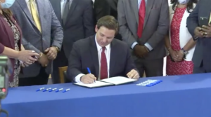 Photo of governor signing a bill at a blue table