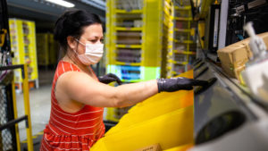 Employee wearing a mask and gloves sorting products in a warehouse