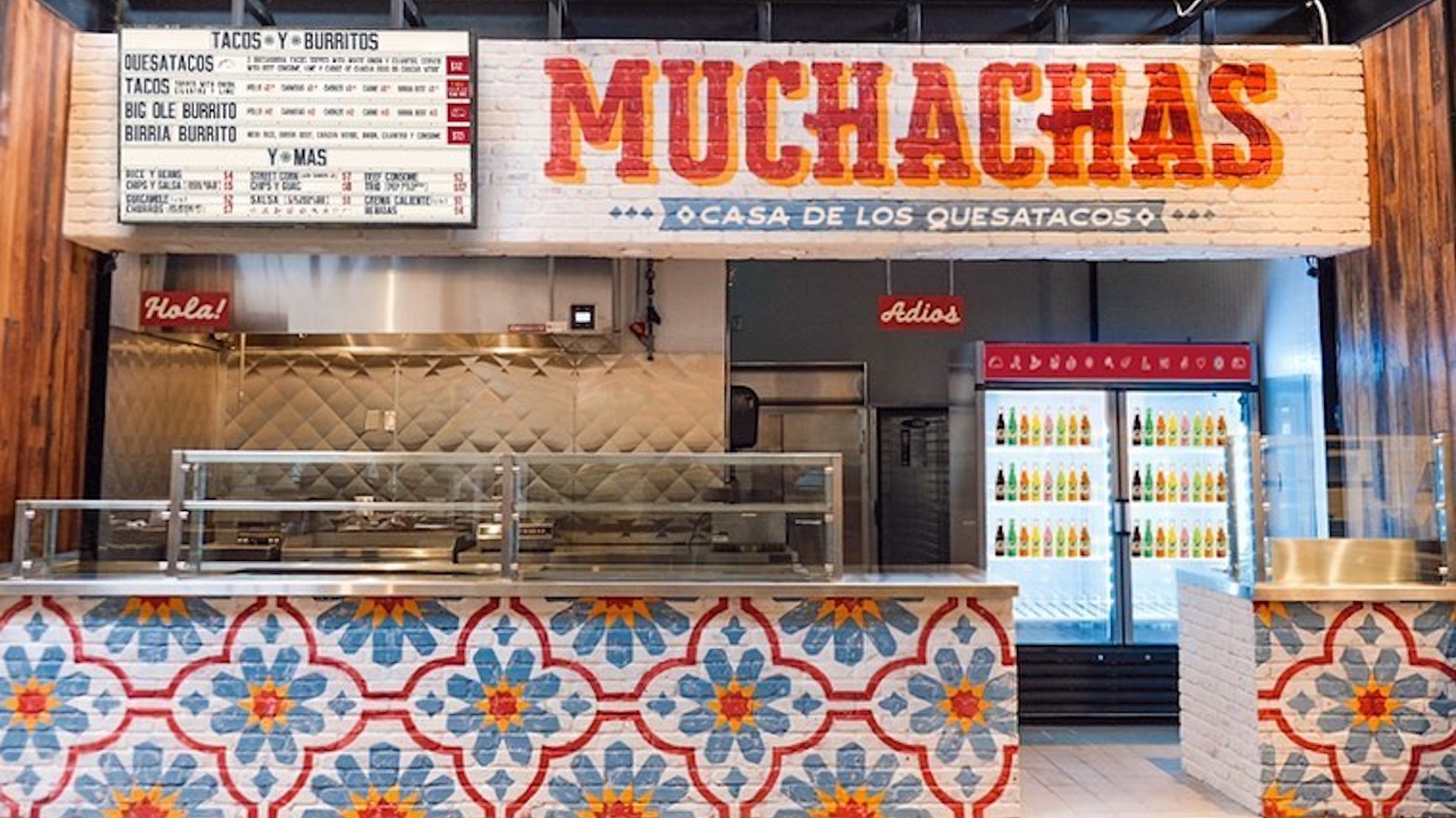 Exterior of a restaurant with a hand painted sign reading "Muchachas"