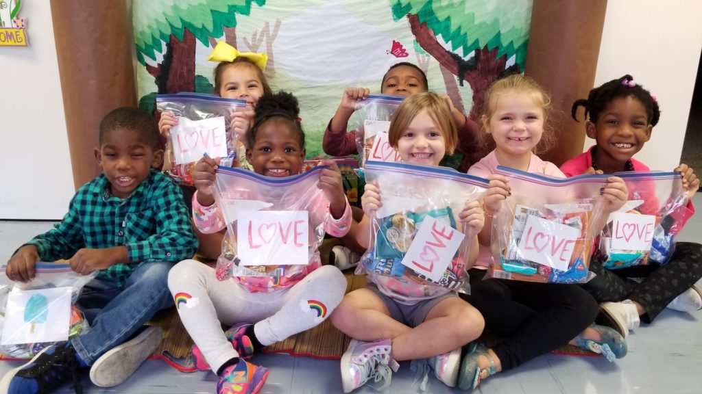 Photo fo young children holding goodie bags with LOVE written on the front
