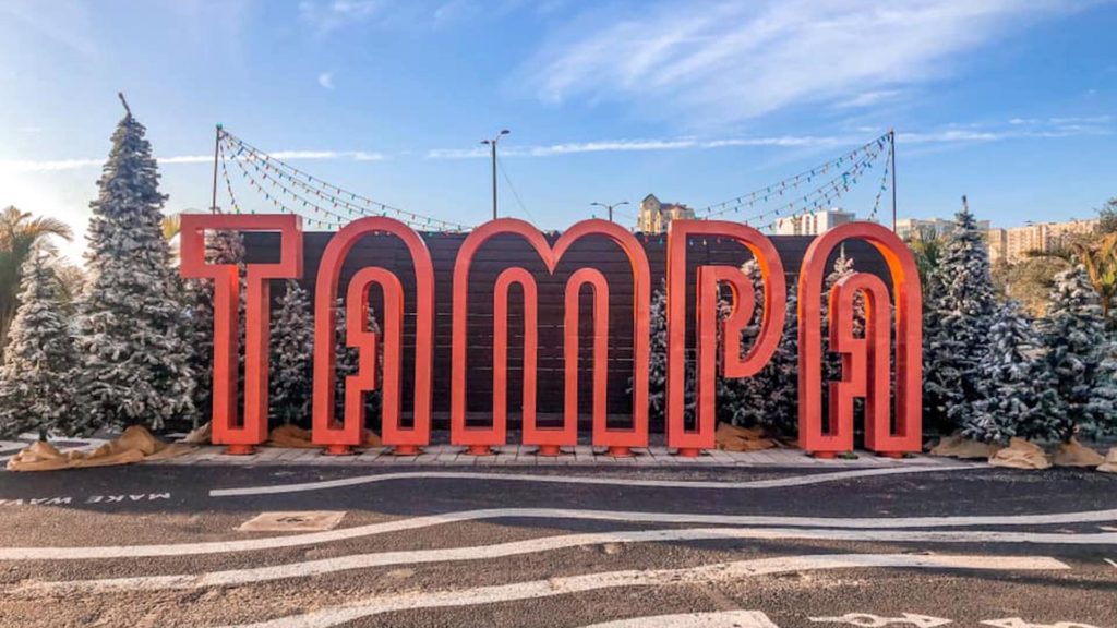 Image of a giant pink Tampa sign surrounded by Christmas trees