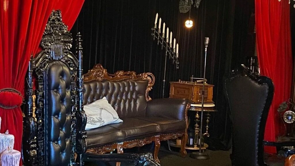 a large letter couch is tucked behind a red velvet curtain. 