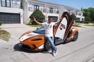 Dilan Jay's beloved McLaren has been repainted to advertise Woke Up! Here, he poses alongside it.