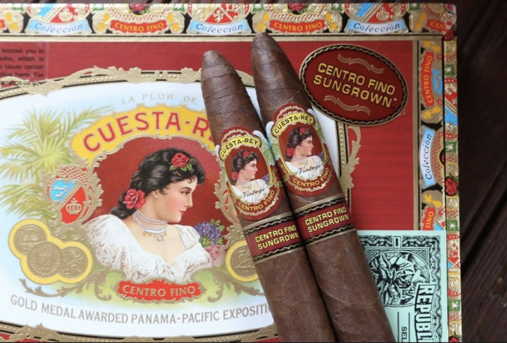 Detailed image of cigars on top of a red cigar box with a woman painted on it. 