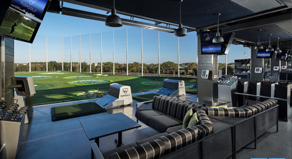 High-tech golf bay with lounge seating and TVs overlooking the driving range.