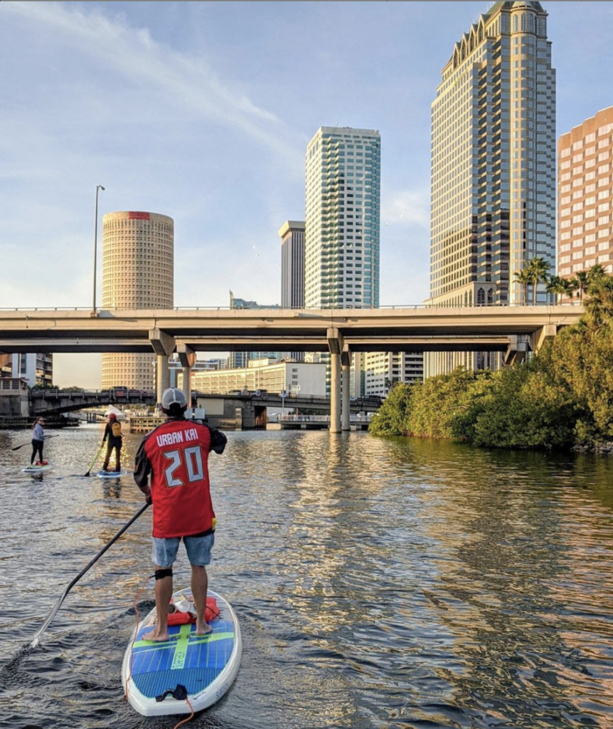 People standing on paddle boards in the river in downtown Tampa.