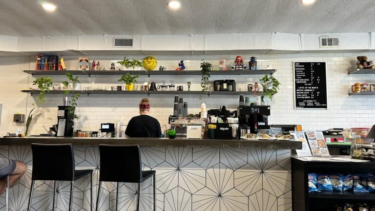 a counter inside a small cafe with flowers and art on the wall.