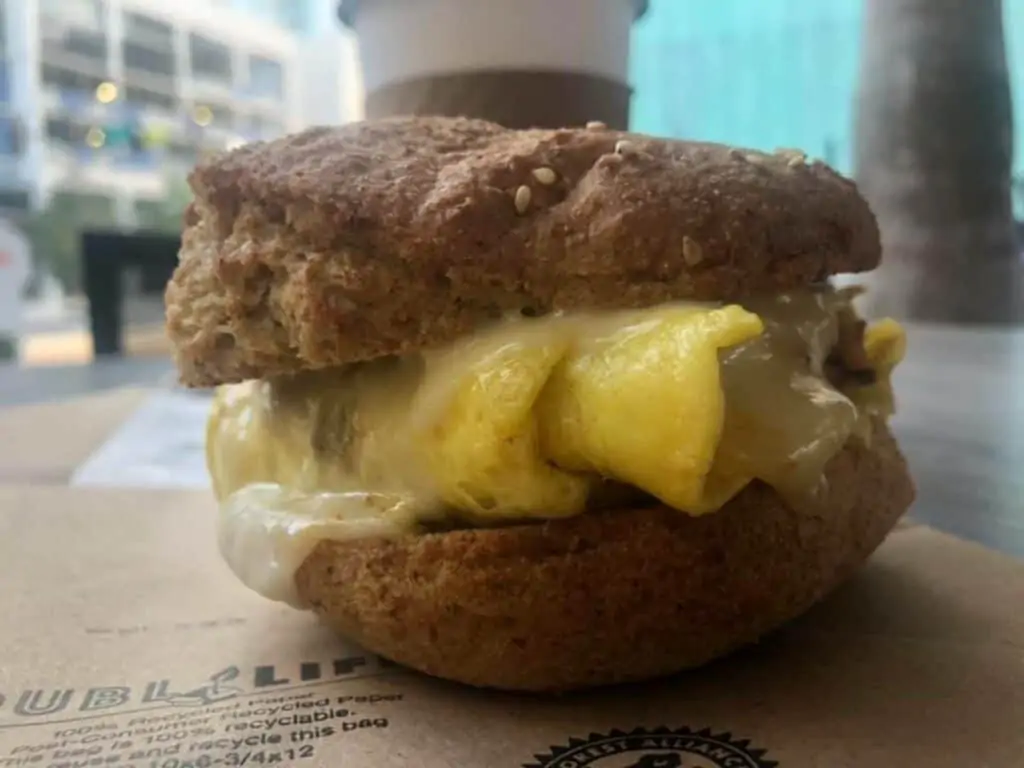 a breakfast sandwich featuring egg, avocado, and chicken sausage