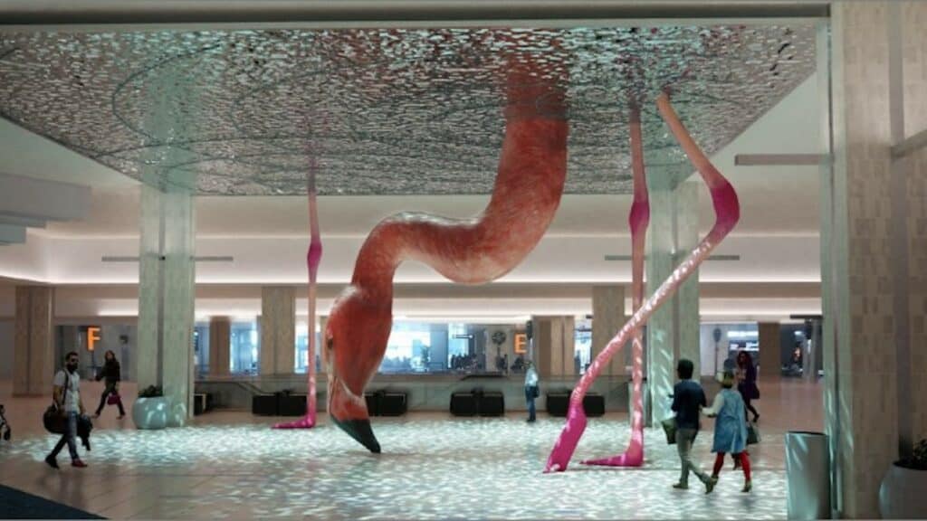 a giant flamingo sculpture with its beak bent toward the ground