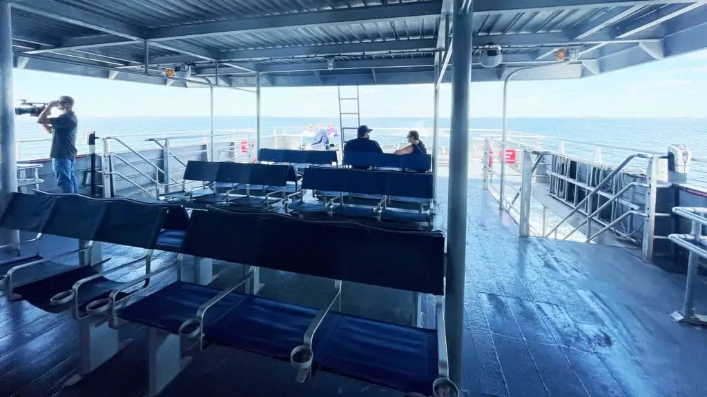 the top deck of the ferry with multiple blue seats available