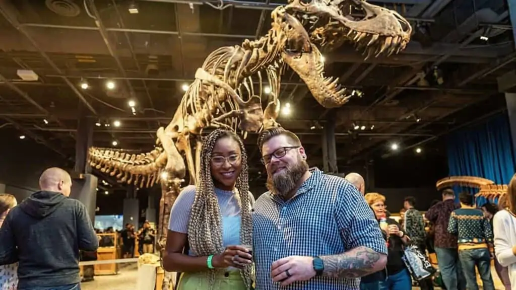 two people standing in front of a dinosaur fossil in a museum