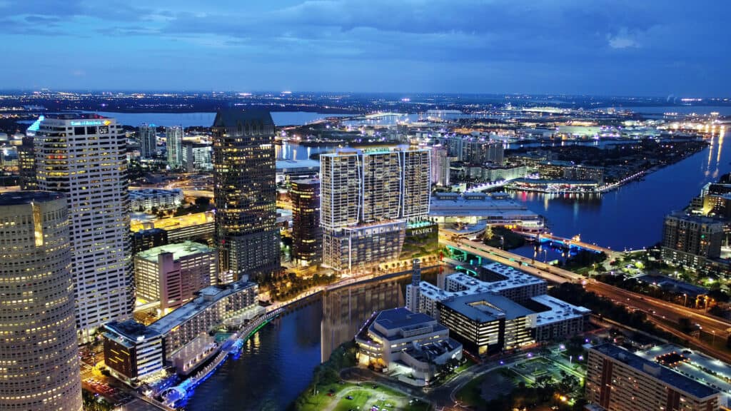 rendering of downtown Tampa with a new hotel lit up on the waterfront in the evening