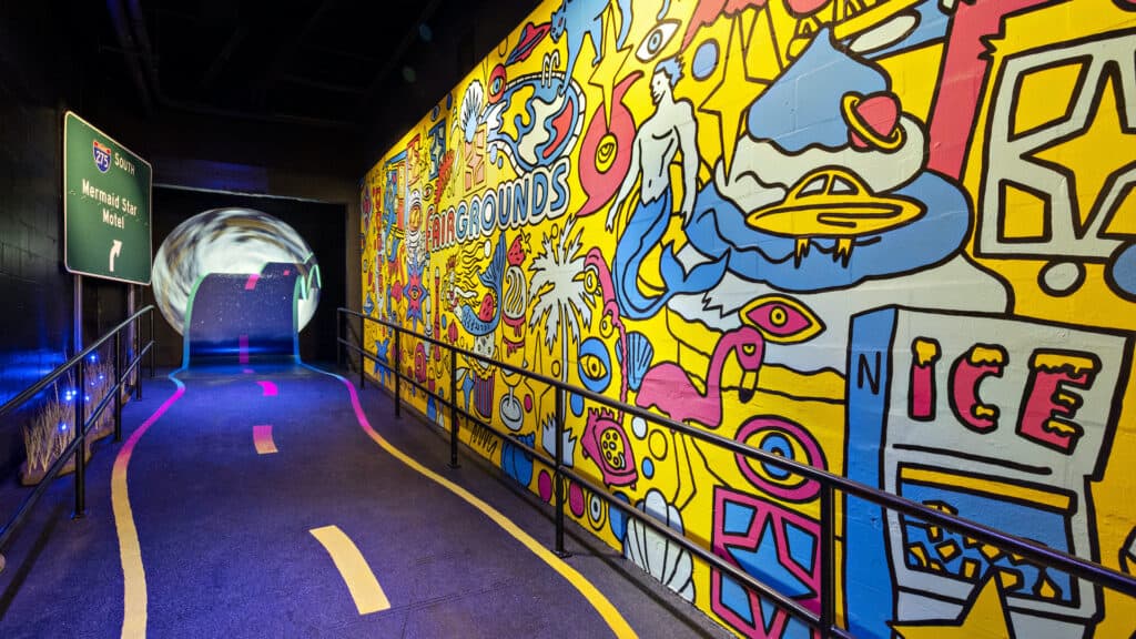 a vibrant mural leads to a projection of a road and a starry sky on a far wall.