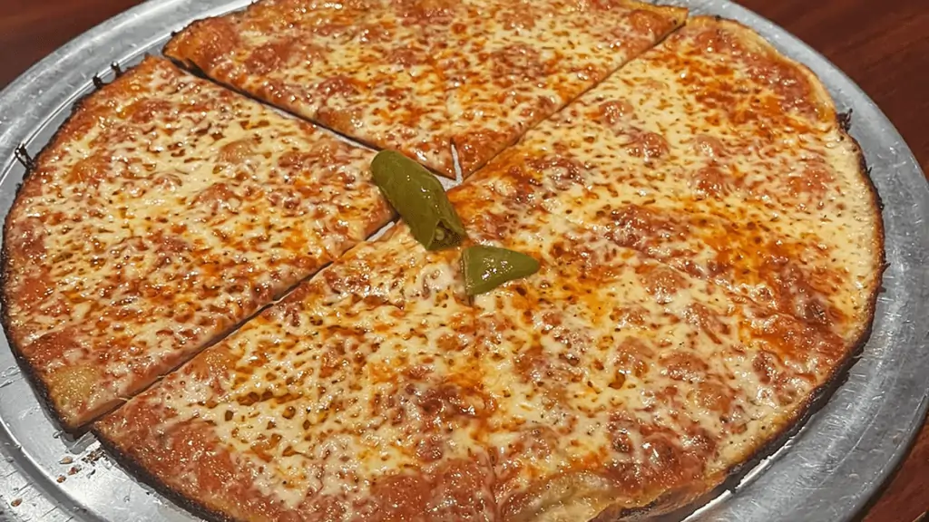 a photo of thing crust cheese pizza covered in hot oil with a pepper at its center