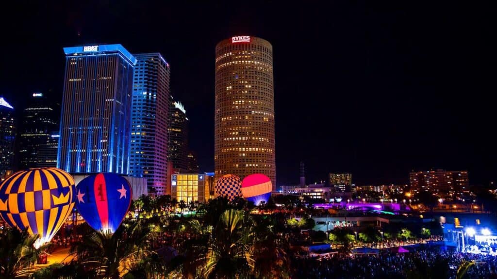 Night time view of downtown with lights and hot air balloons on ground