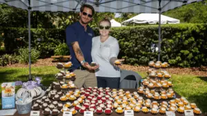 table filled with bundt cakes. Two people are holding bundt cakes.