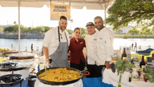 Three chef around a pot of paella at an outdoor food festival