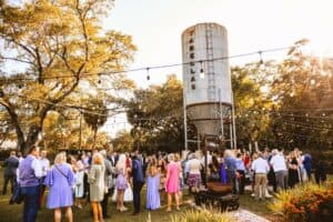 An outdoor events venue with hundreds of people gathered near a rustic water tower