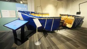 large blue boat covered in a blue tarp next to an interactive computer monitor