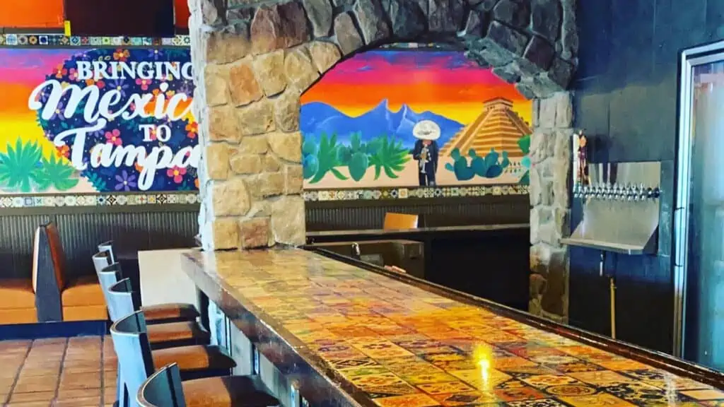 inside a restaurant with a marble bar, and a rainbow mural in the background