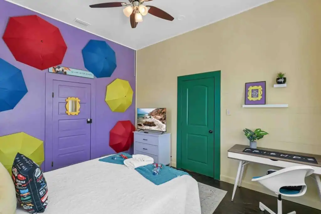 a bedroom with a purple wall, and umbrellas formed like an archway along the wall. 