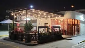 Exterior of a restaurant situated inside an old gas station with a red mural along the front awning.