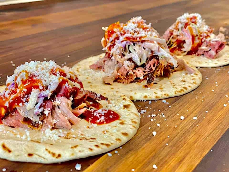 three pulled pork tacos covered in cheese and bbq sauce
