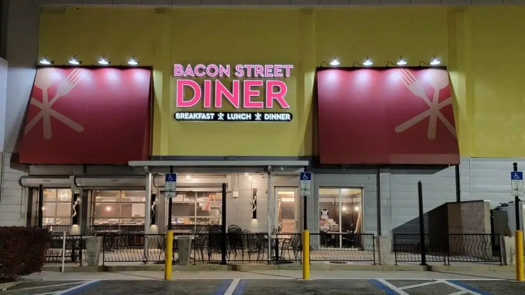 Exterior of a restaurant with a glowing red sign over the awning that reads Bacon Street Diner