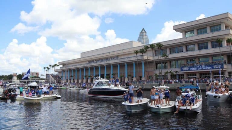 Exterior of a convention center with multiple boats floating in the water