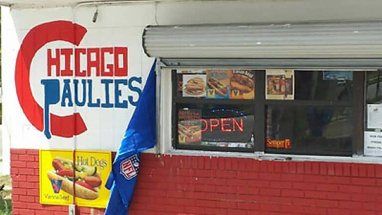 exterior of a hot dog shop with blue and red lettering hand painted on the front