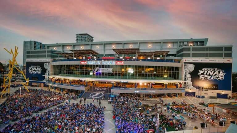 People gathered outside a hockey stadium at sunset.