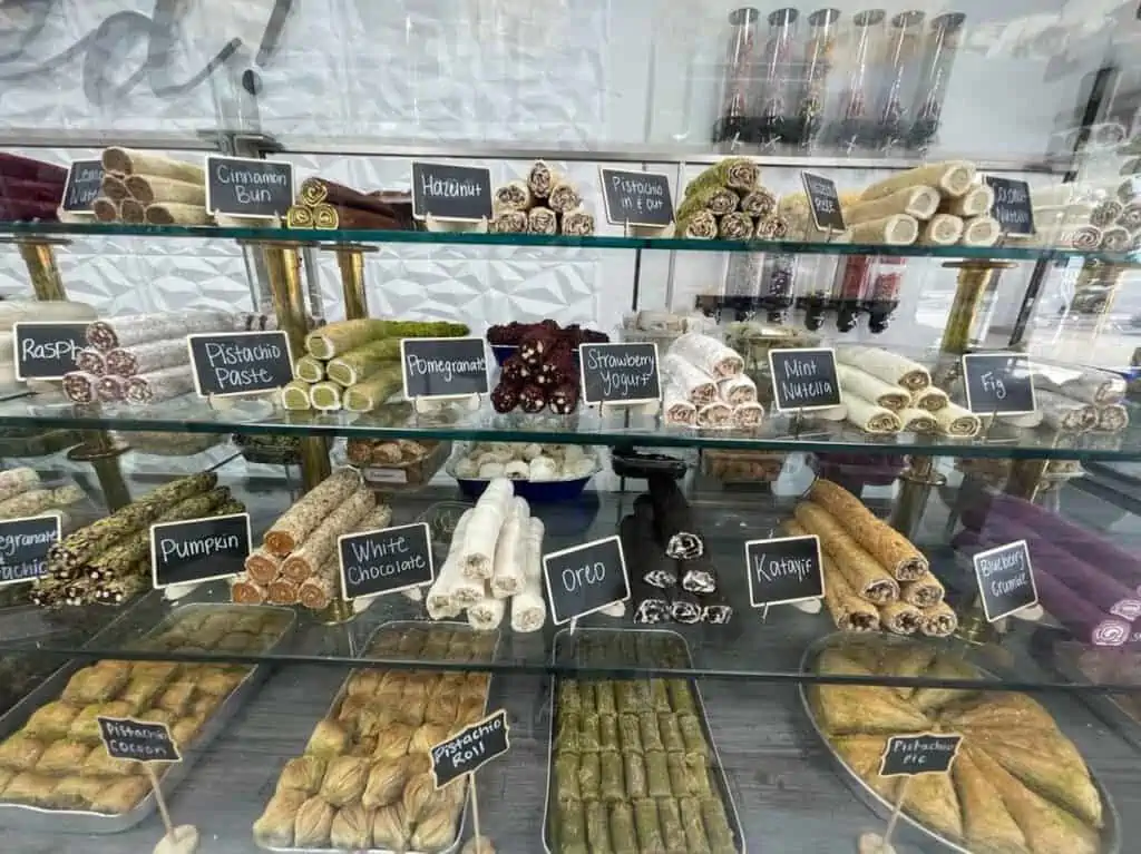 multiple colorful desserts behind a glass case inside a halal candy shop 