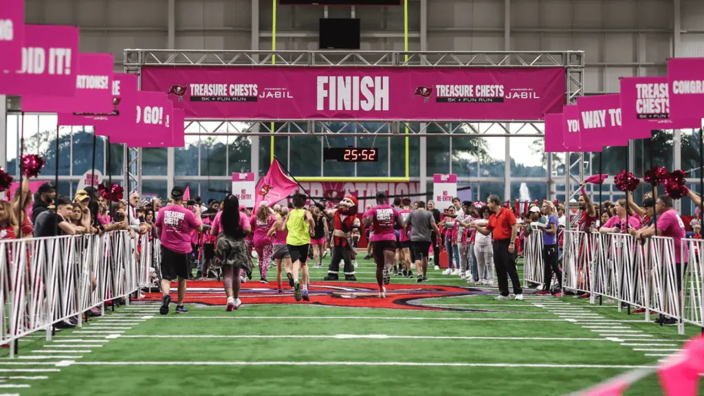 People running in pink on a football field
