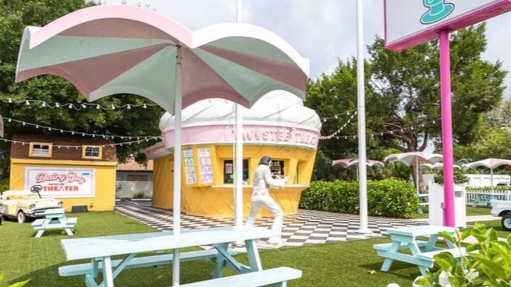 an ice cream cone shaped ice cream parlor with picnic tables out front