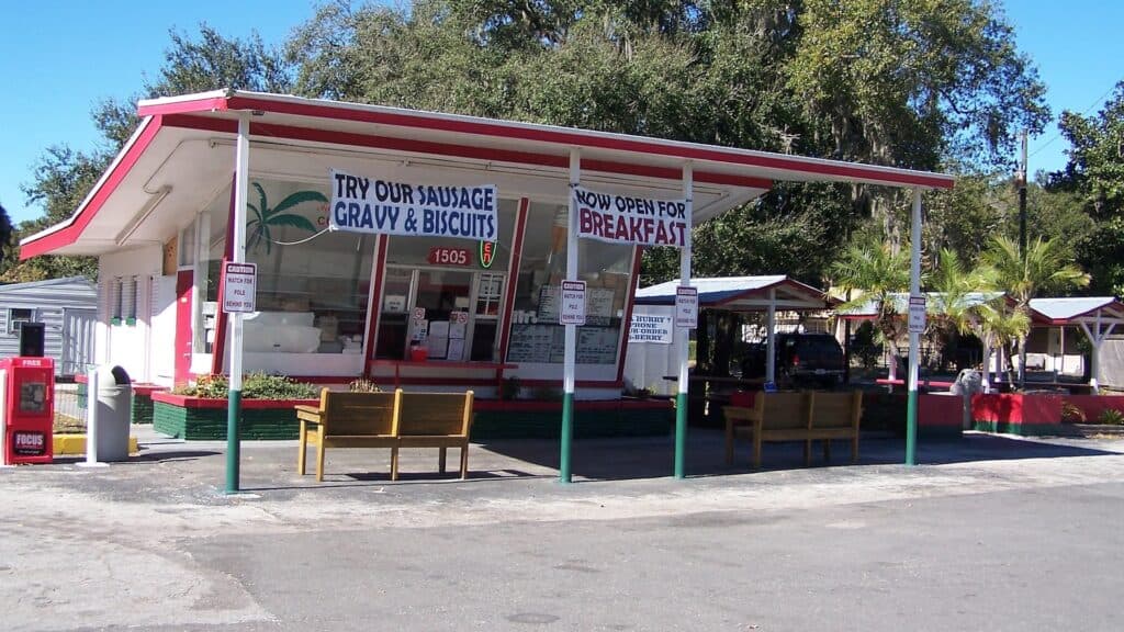Exterior of a roadside farm stand with signs for breakfast and lunch hanging from the exterior