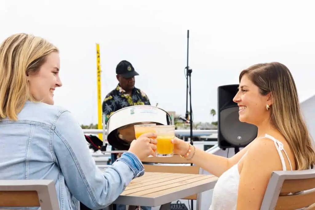 two girls cheersing mimosas on board a boat