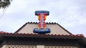 Exterior of a restaurant with a new neon sign. The coloration is orange and blue.