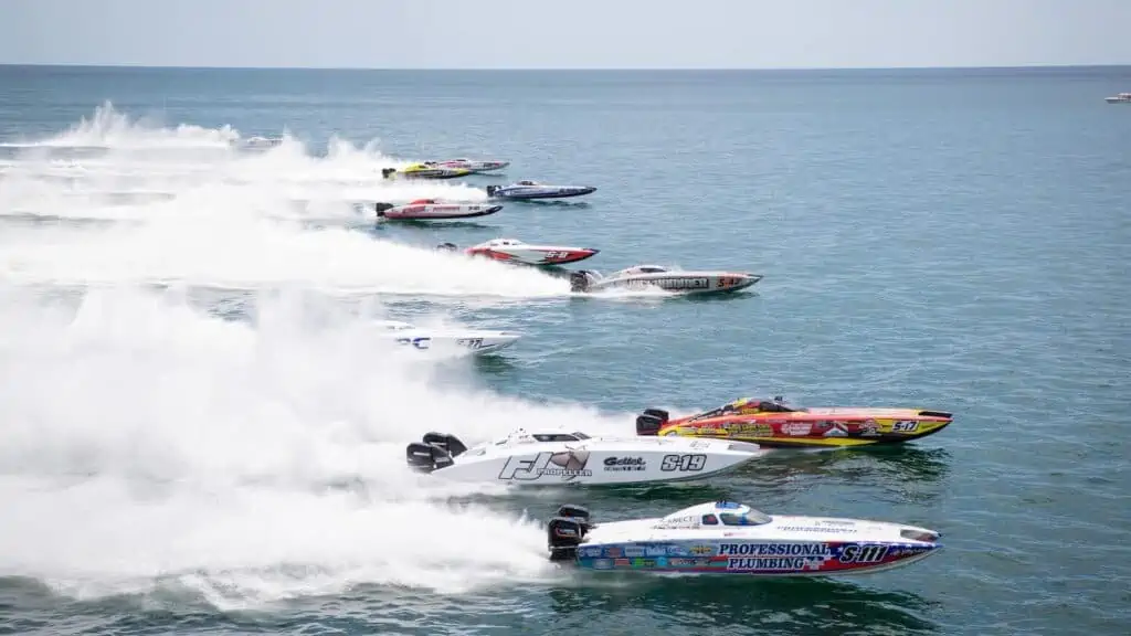 a series of slender powerboats making large wakes in the water.