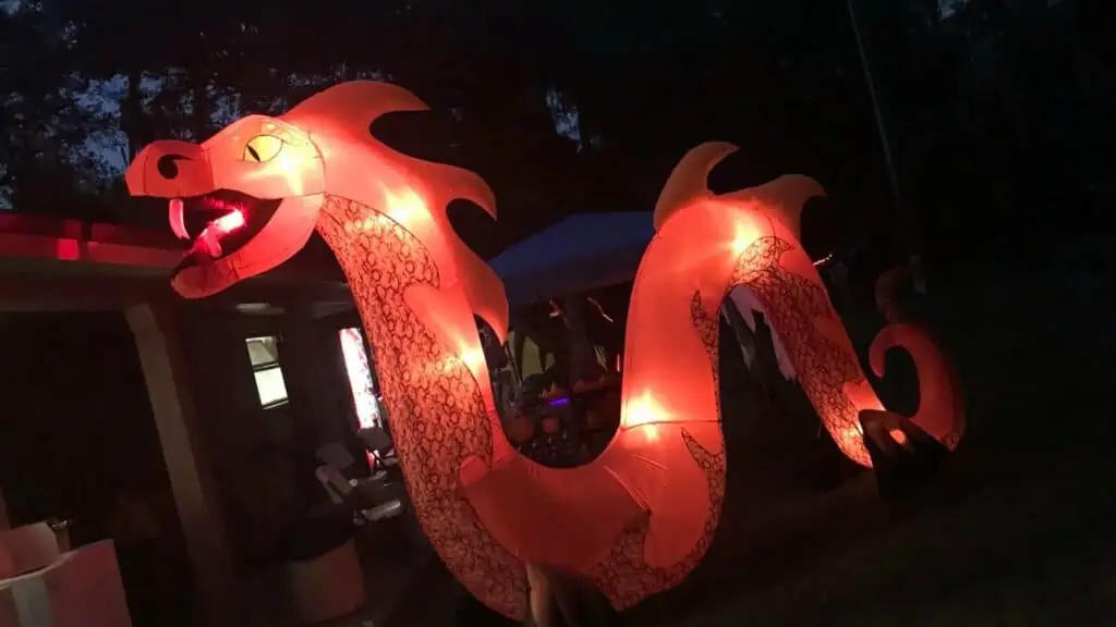 inflatable light up dragon set up in a dark wooded area.